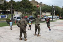 Marine 1stLt. Dallas W. Beatty plays basketball with local children during Discovery Day festivities here March 9. The Marines participated in activities and provided vehicle and weapons displays during the festival. The Marines are part of Exercise Guahan Shield, an exercise designed to facilitate community relations, multiservice engagement, and provide potential response to theater crises and contingency operations in the Asia-Pacific region.