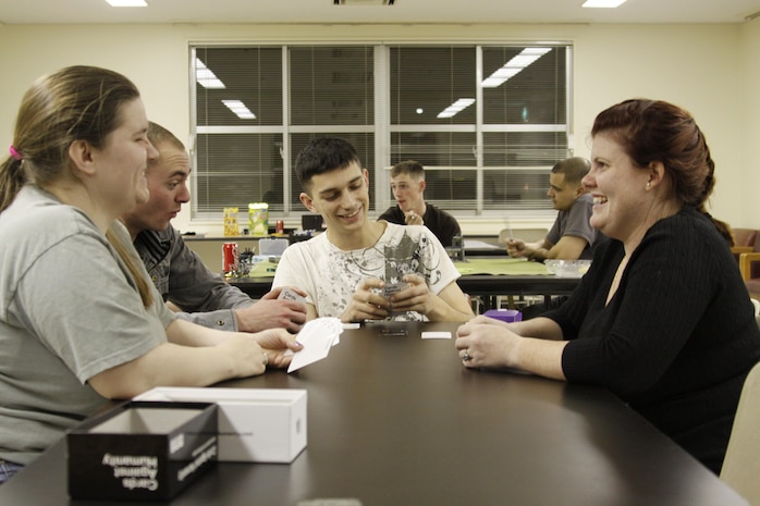 (From left to right) Janis Price, station resident, Lance Cpl. Caleb Just, Headquarters and Headquarters Squadron bulk-fuel specialist, Sgt. Leroy Grubbs, Marine Aviation Logistics Squadron 12 aviation ordinance collateral duty inspector, and Louise Tindel, station resident, play Cards Against Humanity at Yuri Tower here, March 2, 2013. The gaming club plays several games, including table-top strategy games, board games and card games. Those who have no experience playing any of these games are encouraged to participate.