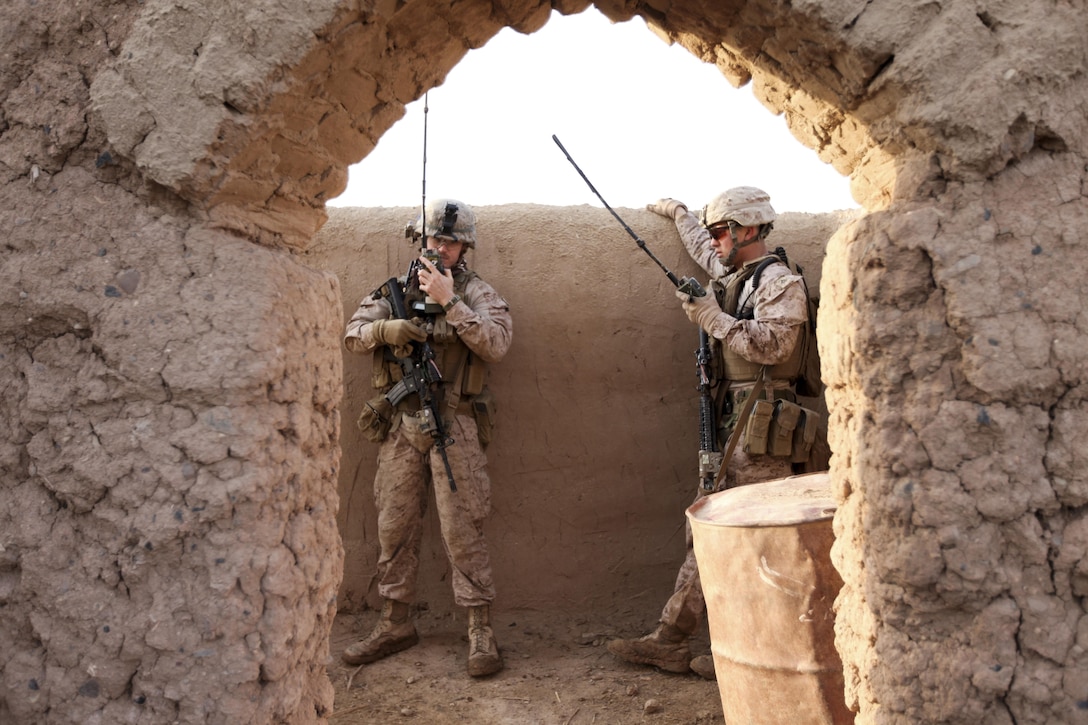 2nd Lt. James Clement and Lance Cpl. Emilio TherienGonzales use their radios to communicate with other Marines from 2nd Battalion, 7th Marine Regiment to locate a shooter who had engaged the unit while they were conducting a sweep of a compound near Patrol Base Boldak March 3. (Photo by Sgt Bobby J. Yarbrough)
