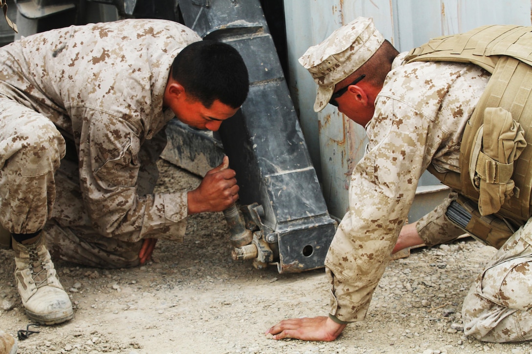 Lance Cpl. Angel Valer (left) and Cpl. Chris Gonzalez, Jr., motor transport operators with 2nd Platoon, Transport Support Company, Combat Logistics Regiment 2, use a large bolt to loosen a nut from an ISO container here, March 8.