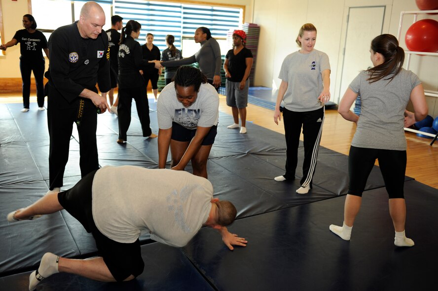 Master Sgt. Sabrina Johnson, middle, 8th Fighter Wing public affairs, practices a self-defense takedown on Staff Sgt. Jonathan Mollison, 8th Comptroller Squadron, as Taekwondo instructor, Edward Kirchmeier instructs her at Kunsan Air Base, Republic of Korea, March 6, 2013. Twelve women and seven men attended this class sponsored by the Sexual Assault Response Coordinator for Women’s History Month to practice self-defense techniques. (U.S. Air Force photo by Senior Airman Marcus Morris/Released)