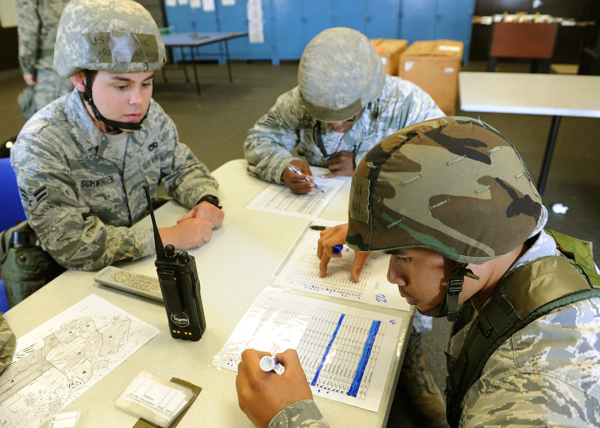 Airman 1st Class Karl Schwinger, 15th Aircraft Maintenance Squadron avionics mechanic (left), Staff Sgt. Jermaine Tate, 15th Aircraft Maintenance Squadron communications navigation (center) and Master Sgt. Elijah Tiqui, 154th Hawaii Air National Guard  Aircraft Maintenance Squadron hydraulics (right) check their manning accountability sheets at the C-17 Aircraft Maintenance Squadron entry control point during an Operational Readiness Exercise, Joint Base Pearl Harbor-Hickam, Hawaii, March 8, 2013.  OREs focus on testing the ability of Airmen to don mission-oriented protective posture, or "MOPP" gear, and survive simulated chemical attacks in an austere environment while still proceeding with the mission.  (U.S. Air Force photo/Tech. Sgt. Jerome S. Tayborn)