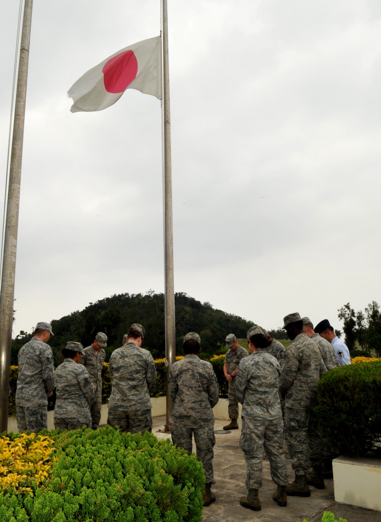 Brig. Gen. Matt Molloy, 18th Wing commander, and members of the command staff take a moment of silence at the Kadena Air Base flag pole at 2:46 p.m. March 11, 2013, to honor and remember those who were lost during the Great East Japan Earthquake in 2011. The Japanese national flag was flown at half staff in remembrance. (U.S. Air Force photo/Naoto Anazawa)