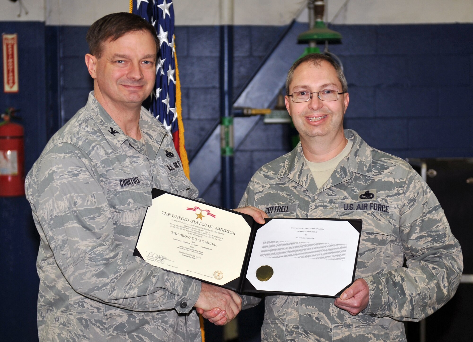Chief Master Sgt. Glen Cottrell, 55th Maintenance Group superintendent, poses with Col. Daniel Courtois, 55th MXG commander, following a Bronze Star ceremony March 8 at the Bennie Davis Maintenance Facility on Offutt Air Force Base, Neb. Cottrell earned the medal by distinguishing himself as superintendent of the 455th Expeditionary Maintenance Group at Bagram Airfield, Afghanistan, from Jan. 26, 2012 to Aug. 4, 2012. His stalwart efforts guaranteed protection for International Security Assistance Forces directly engaged with enemy insurgents through the employment of 379 precision guided munitions and more than 120,000 rounds of ammunition, as well as rapid response to 734 Troops In Contact situations. (Photo by Jeff Gates/Released)