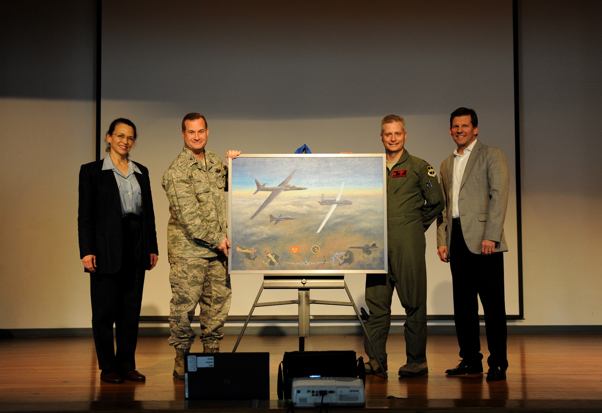 Aviation artist Kristin Hill (left) and Dave Schmall (right) present Col. Phil Stewart, 9th Reconnaissance Wing commander and Lt. Col. Stephen Rodriguez, 1st Reconnaissance Squadron commander with a painting depicting the centennial of the 1st RS at Beale Air Force Base, Calif., March 7, 2013. The painting features many aircraft flown by the 1st RS including the U-2 “Dragon Lady” and SR-71 Black Bird. (U.S. Air Force photo by Staff Sgt. Robert M. Trujillo/Released)