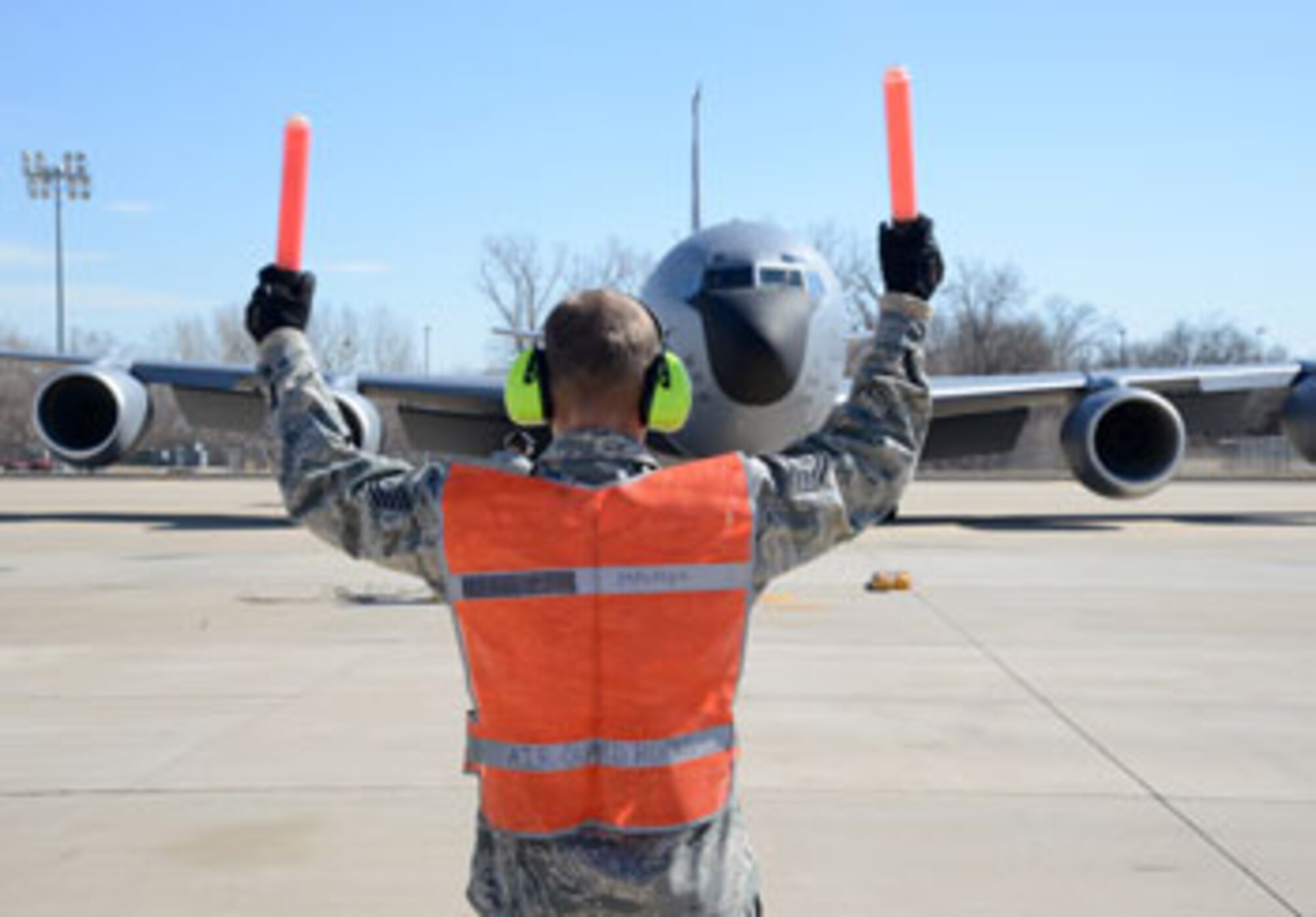 Tech. Sgt. Casey Ray, a crew chief with the 137th Aircraft Maintenance Squadron, marshals a KC-135 Stratotanker into a parking spot. (Air Force photo by Kelly White)