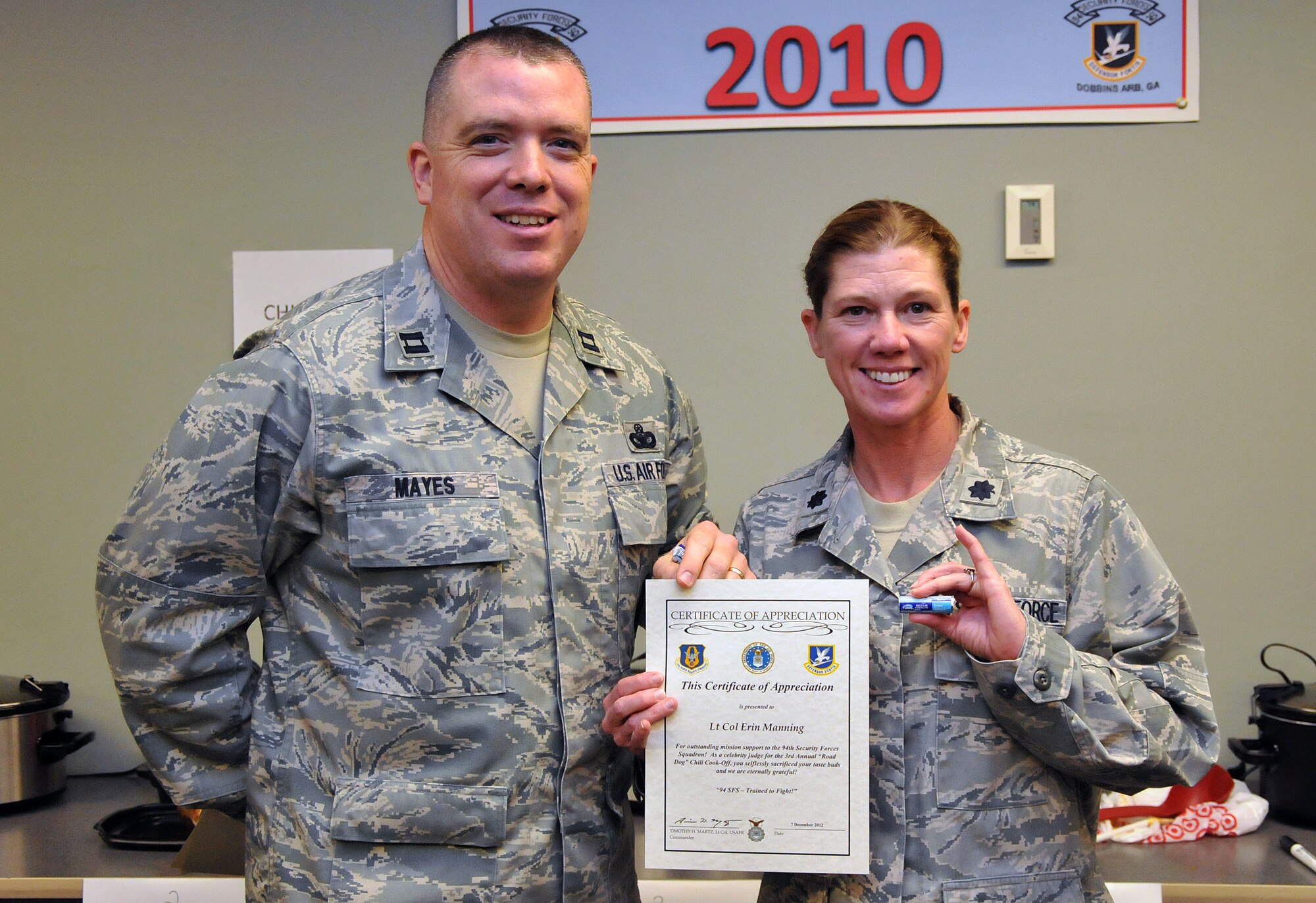 Lt. Col. Erin Manning, 94th Mission Support Group deputy commander, proudly accepts her certificate of appreciation from Capt. Robert Mayes, 94th SFS operations officer, and appreciates her ration of Tums. The Third Annual 94th Security Forces Squadron Chili Cook-off was guarded against tampering at the 94th SFS building on Dec. 12. (U.S. Air Force photo/Senior Airman Elizabeth Van Patten)