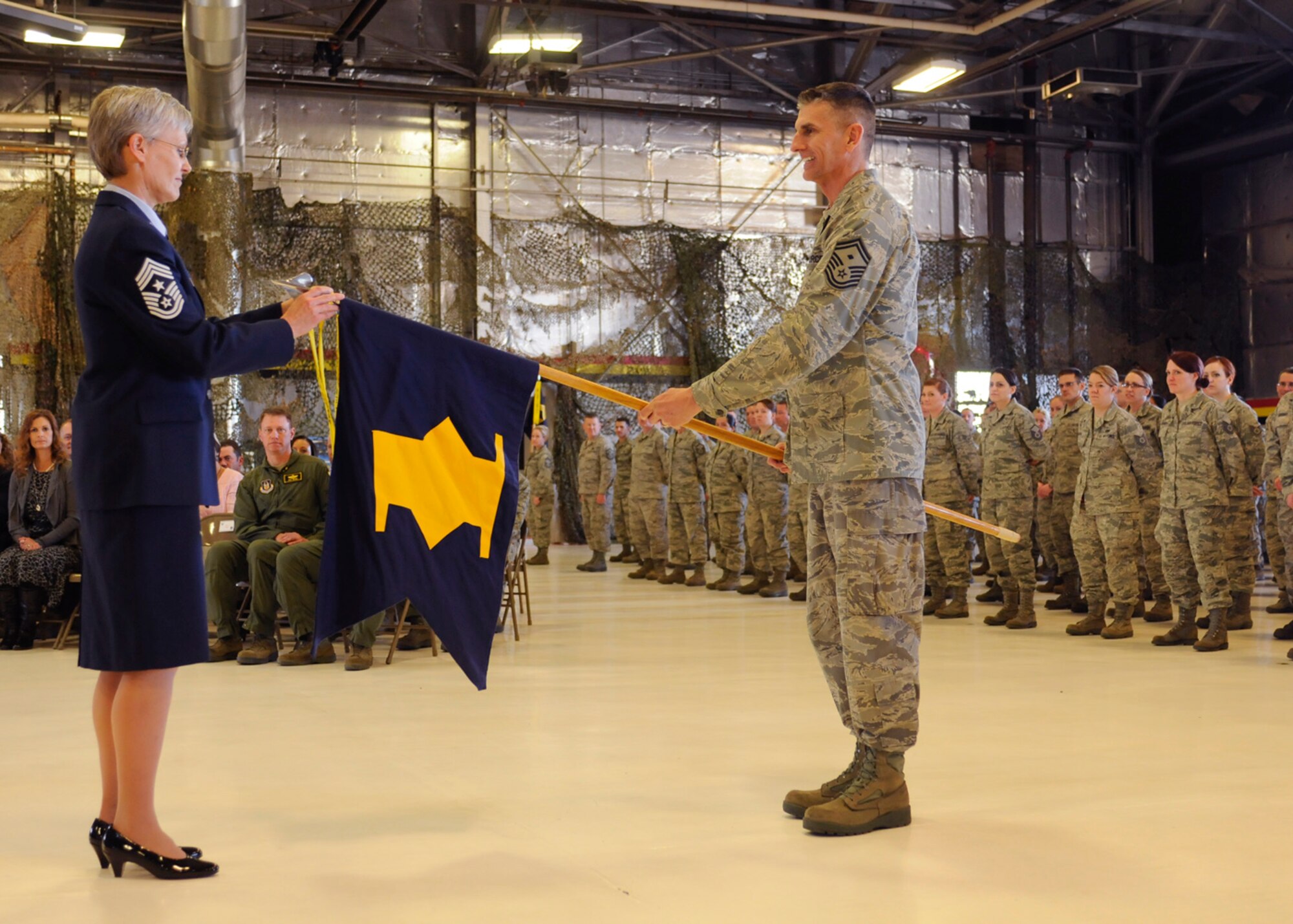 Chief Master Sgt. Cindy George, 419th Fighter Wing command chief, places her streamer onto a flag held by Senior Master Sgt. Christopher Sayre, 67th Aerial Port Squadron first sergeant, during the chief’s retirement ceremony here Sunday. The streamer bears her name and indicates she served honorably as a first sergeant. (U.S. Air Force photo/Staff Sgt. Heather Skinkle)