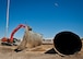 An excavator picks up a flattened piece of a 50,000 gallon underground fuel storage tank as a C-130 flies overhead near the 33rd Fighter Wing March 11 at Eglin Air Force Base, Fla.  The tank was one of four removed from the area.  The systems have been in place since 1959 and formerly used to refuel 33rd FW aircraft until recently.  The new fuel storage system is already in place and increases the wing's capacity to more than a million gallons of JP-8 for the F-35s.  (U.S. Air Force photo/Samuel King Jr.)