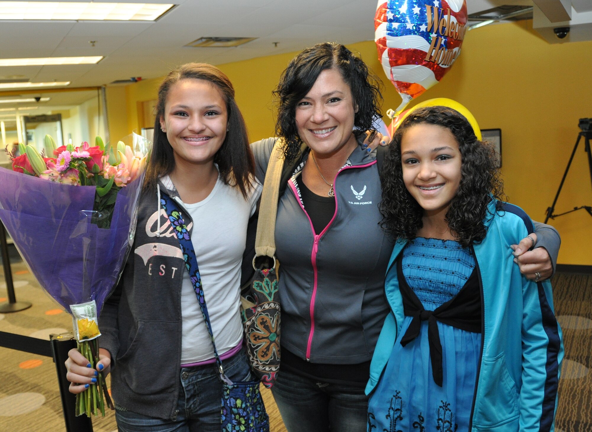 Tech Sgt. Frances Kness, Band of the U.S. Air Force Reserve vocalist, hugs her daighters Deandra and Jade at the Macon Regional Airport March 8. Kness and five of her fellow bandsmen just completed a nearly four-month deployment to Southwest Asia, criss-drossing the area of operations to perform for the troops and to spread goodwill throughout the region. Their return marked the final deployment for the band, which will be deactivated at the end of September 2013. (U.S. Air Force photo/Philip Rhodes)