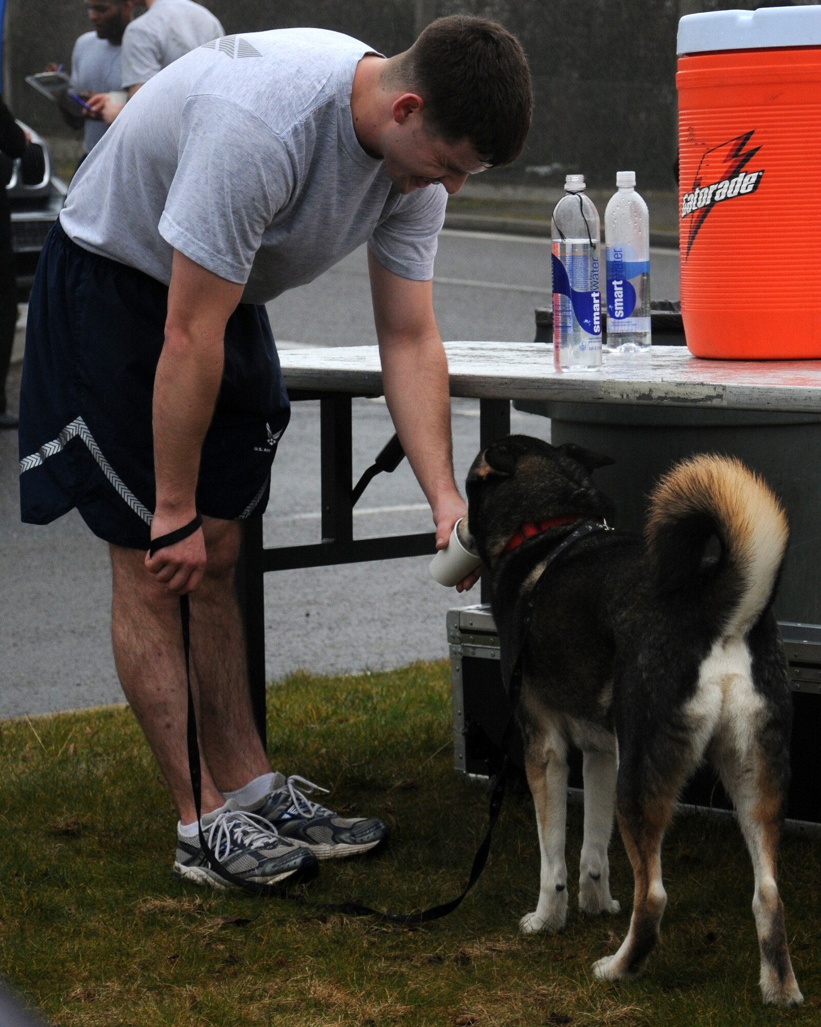 A Team Mildenhall Airman offers his dog a drink of water following a wing run March 8, 2013, on Perimeter Road near the Hardstand Fitness Center on RAF Mildenhall, England. Through exercise and healthy competition, the 5K runs promote morale. (U.S. Air Force photo by Gina Randall/Released)