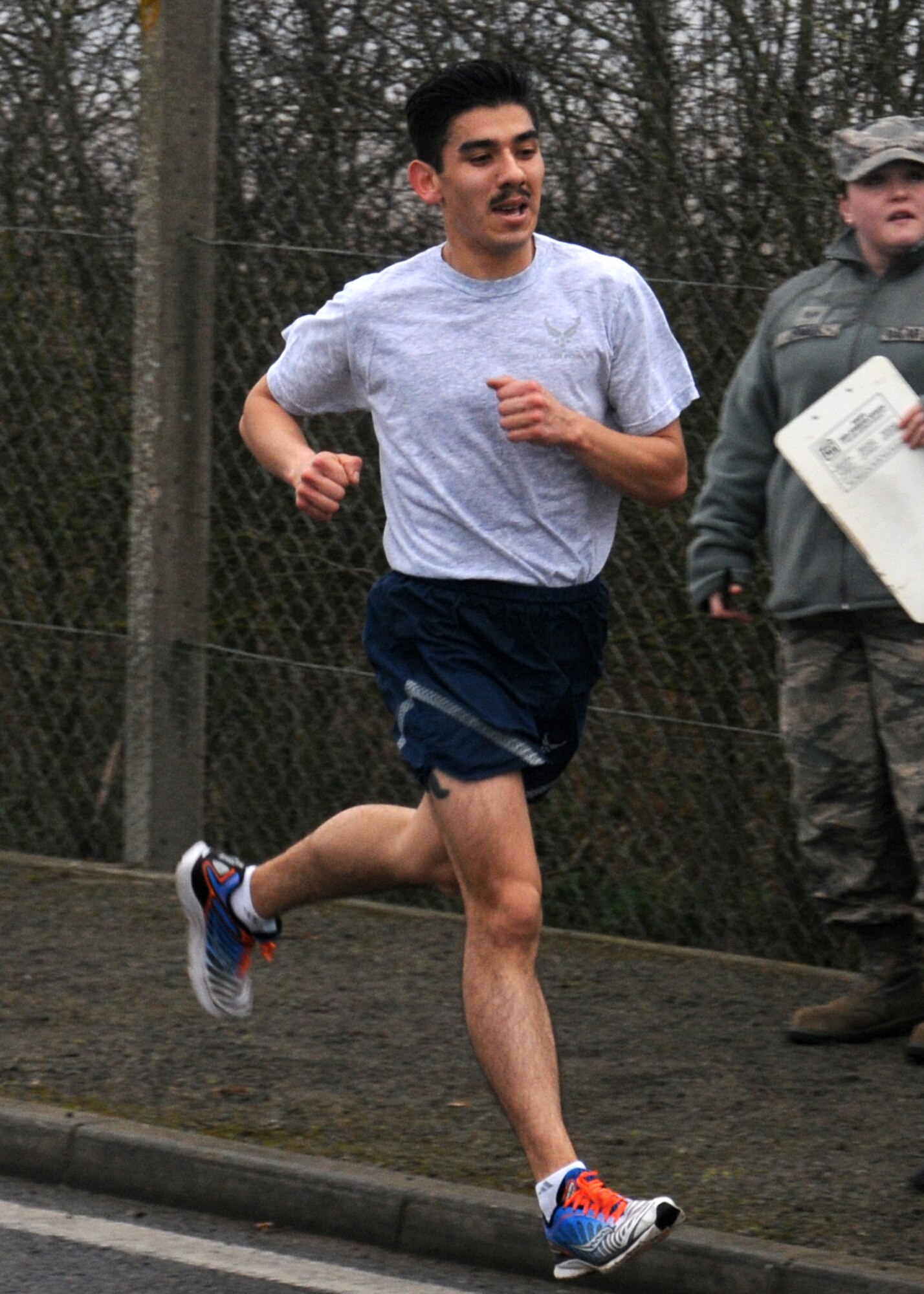 Senior Airman Julio Villa, 100th Maintenance Squadron aircraft structural maintenance from Sacramento, Calif., is the first male to cross the finish line at a wing run March 8, 2013, on Perimeter Road near the Hardstand Fitness Center on RAF Mildenhall, England. Villa finished the run with a time of 18:11. The run began at the south-end of the parking lot and was an opportunity for personnel to test their fitness levels, as well as have a goal to work toward. (U.S. Air Force photo by Gina Randall/Released)