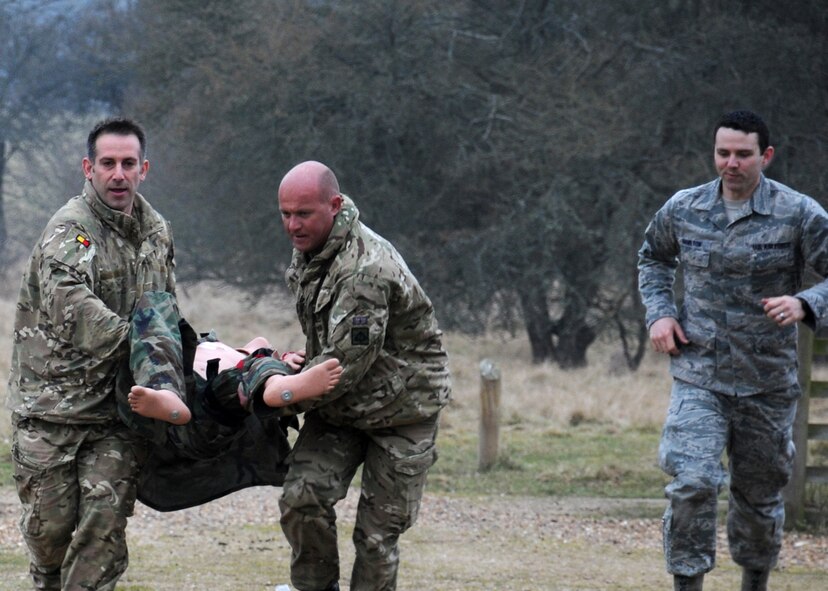 Staff Sgt. Tyler Hamilton, right, 352nd Special Operations Support Squadron independent medical technician from Naples, Fla., advises British Army members Sgt. Jay Eggleton, left, from Bury St. Edmunds, Suffolk, and Sgt. Daz Sobey, center, from Plymouth, Devon, both 19 Regiment Royal Artillery U.K. Joint Tactical Air Controllers on how to move a patient to safety if fired upon March 6, 2013, at Stanford Training Area, near Thetford, England. Throughout the day a mannequin was first used then the U.S. military members played the role of casualties in need of medical assistance in the simulated attacks. (U.S. Air Force photo by Gina Randall/Released)