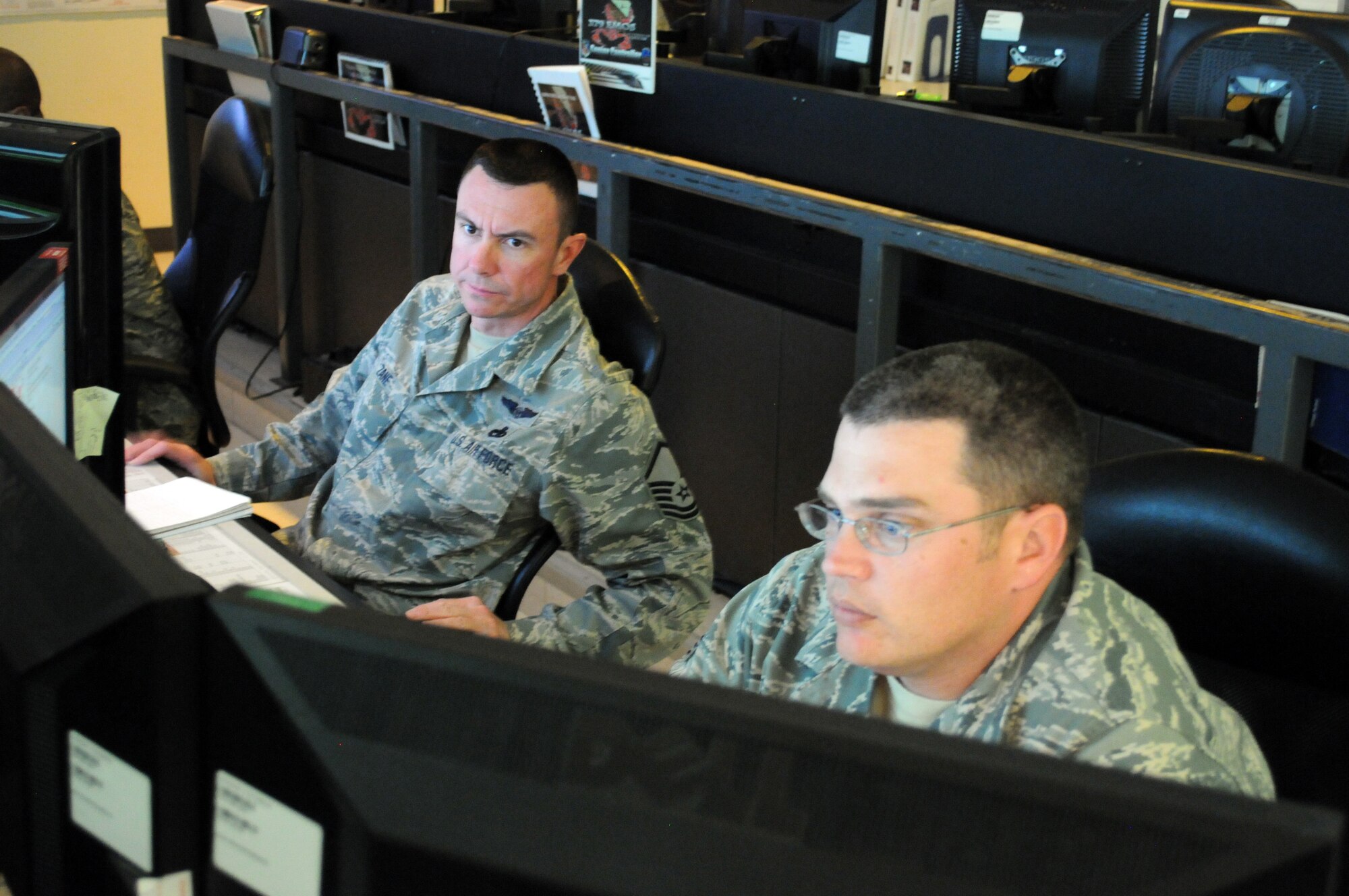 Master Sgt. Scott Zane, KC-135B maintenance operations center controller, helps Staff Sgt. Adam Bishop, KC-135B MOC controller, Mar. 7. The 379th Expeditionary Maintenance Group MOC manages all maintenance operations for units assigned to the 379th Air Expeditionary Wing, ranging from scheduling maintenance, preventing loss of covering by staggering non-maintenance activities, and upchanneling important information to appropriate leadership to make informed operational decisions. (U.S. Air Force photo/Master Sgt. Christian Michael)