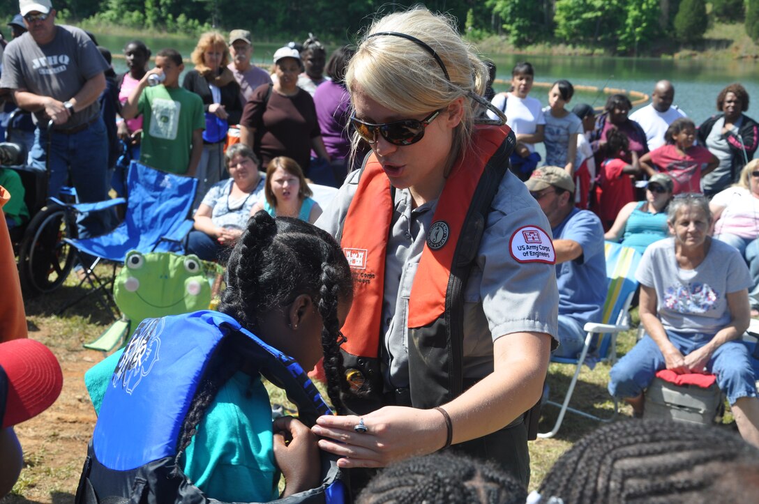 U.S. Army Corps of Engineers Park Ranger Erin Parnell helps a child put on a life jacket during a public water safety demonstration at Richard B. Russell Dam and Lake.