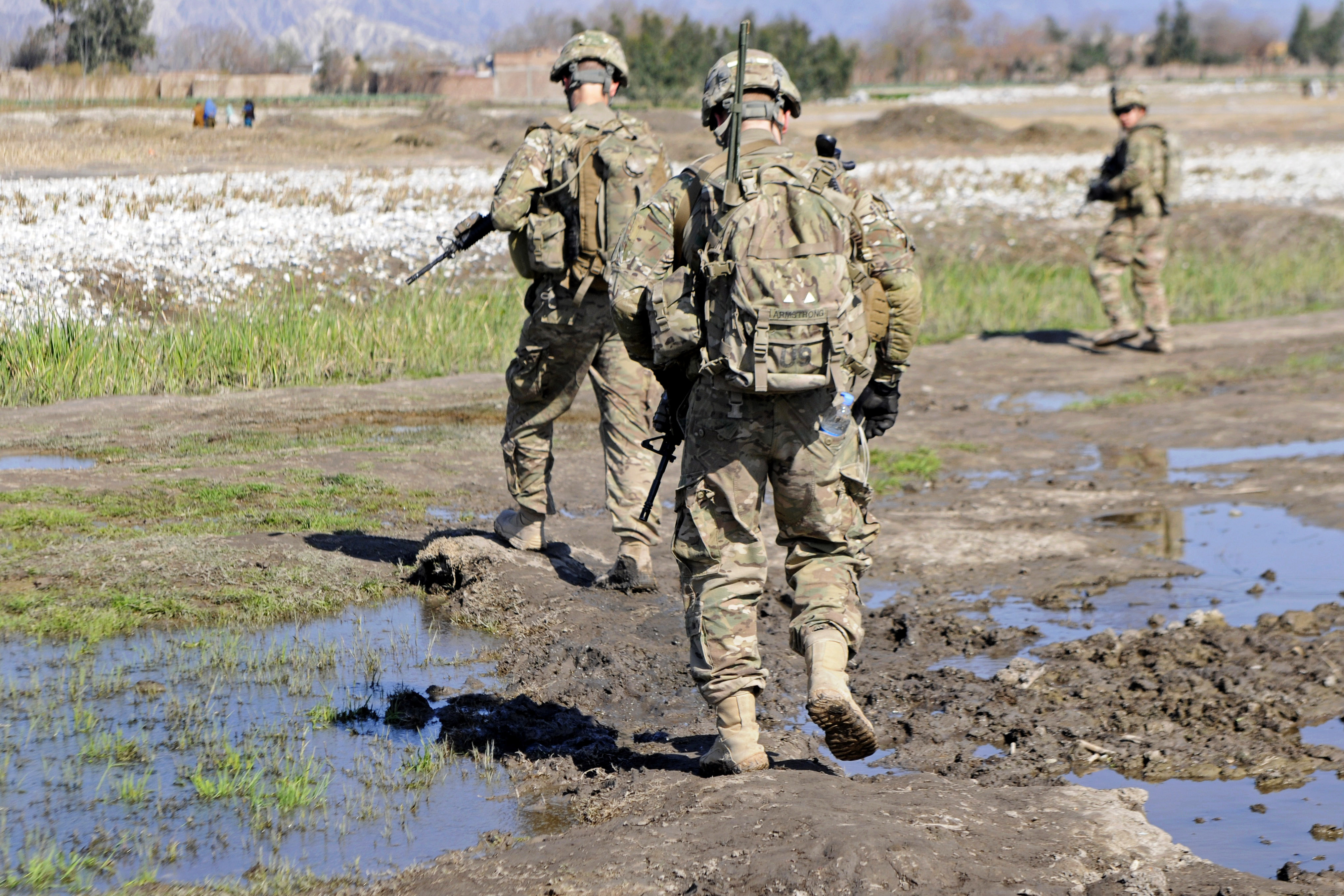 U.S. soldiers walk across a narrow mud bridge during a dismounted patrol outside Forward