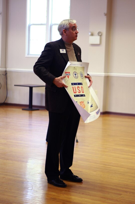 John Falkenbury, the USO of North Carolina president, unveils a poster given to the Marines and sailors with 2nd Supply Battalion, 2nd Marine Logistics Group during a ceremony at the USO in Jacksonville, N.C., March 7, 2013. The battalion collected more than 6,000 pounds of nonperishable food items to help the facility support people in need.