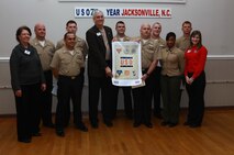 John Falkenbury (center, left), the USO of North Carolina president, poses for a photo with Marines and sailors with Medical Logistics Company, 2nd Supply Battalion, 2nd Marine Logistics Group during an award ceremony at the USO in Jacksonville, N.C., March 7, 2013. Several servicemembers with the company volunteered to update the USO’s storage area after donating more than 6,000 pounds of nonperishable food items.