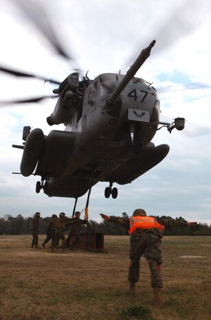 A landing support specialist guides a CH-53E Super Stallion over its simulated cargo load during a field exercise conducted by Combat Logistics Battalion 6, 2nd Marine Logistics Group aboard Camp Lejeune, N.C., Feb. 28, 2013. The battalion conducted the helicopter support training to familiarize some of its personnel with the basics of conducting operations with helicopters in the field. 