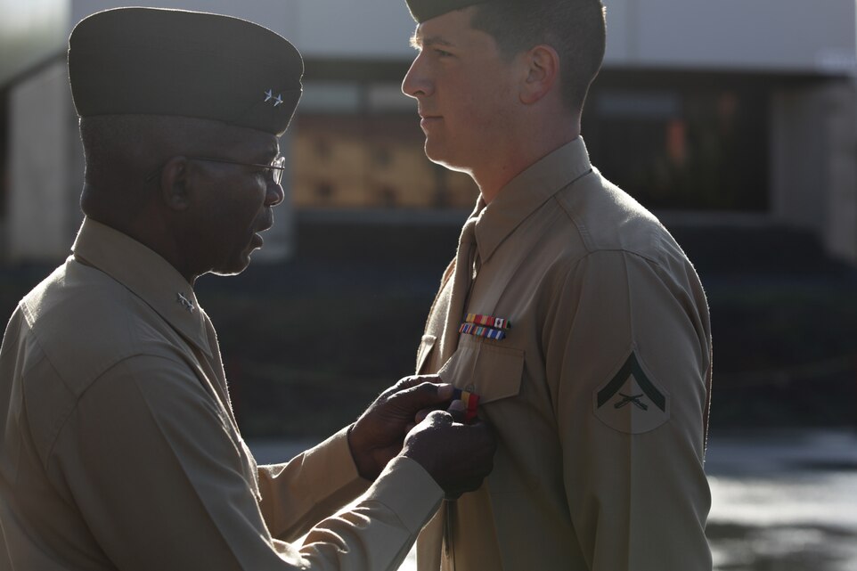 Major Gen. Ronald Bailey, commanding general of 1st Marine Division, pins the Navy and Marine Corps Medal on Lance Cpl. Benjamin Nalls, a fire team leader with 1st Light Armored Reconnaissance Battalion, here, March 8, 2013. Nalls received the medal for saving the life of Sgt. Erick Gutierrez, a squad leader with 1st LAR, during a patrol in Helmand province, Afghanistan. Nalls fell into a nine-foot-deep, 15-foot-wide canal, and was being treated for hypothermia when he learned that Gutierrez had also fallen in the canal. He immediately jumped back into the frigid water and dragged Gutierrez to the riverbank, saving his life.