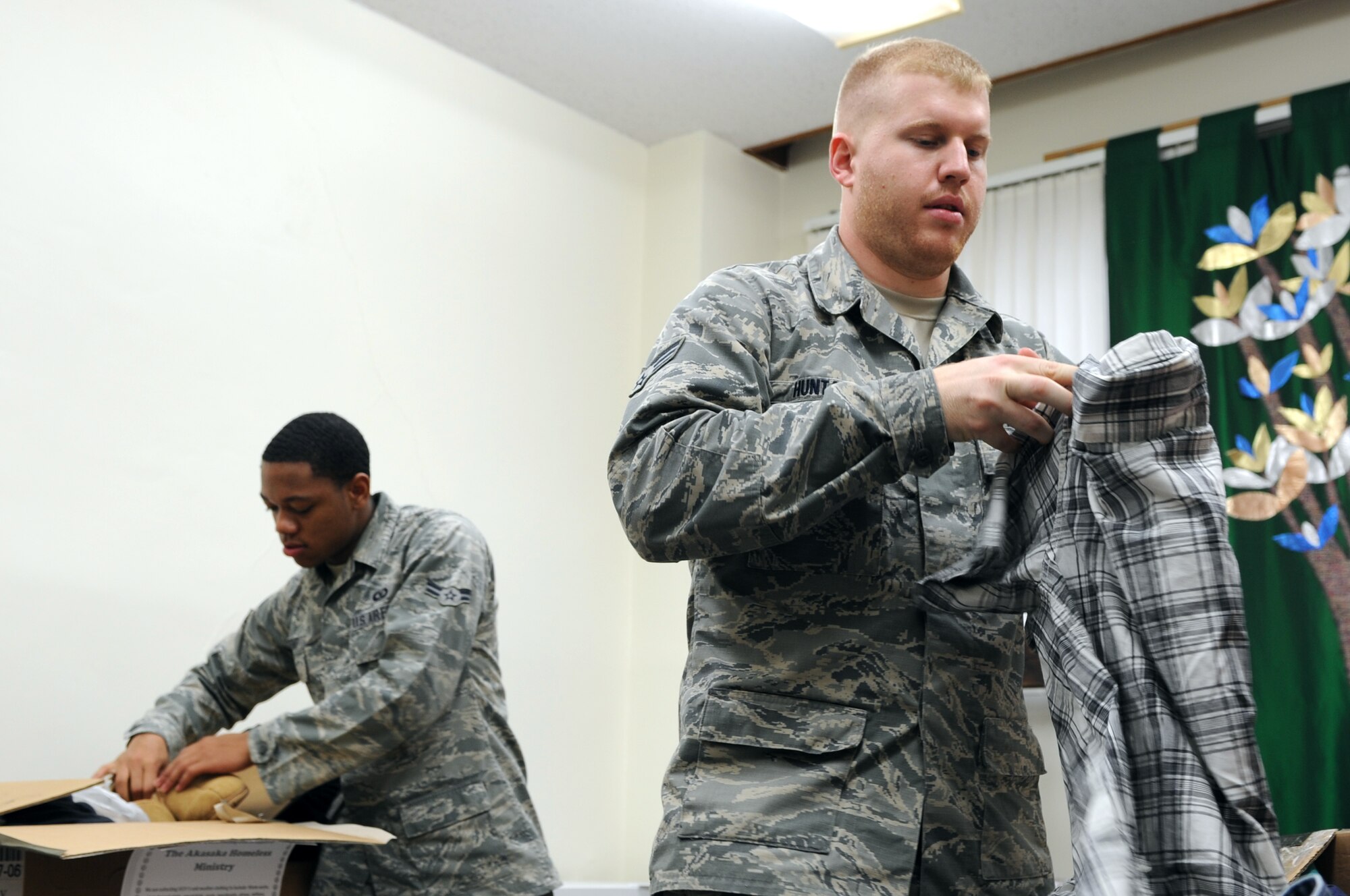 YOKOTA AIR BASE, Japan -- Right to left, Senior Airman Andrew Huntamer and Airman 1st Class Courtland Stewart, both of the 374th Operations Support Squadron, fold and sort items collected during a warm clothing drive March 8, 2013, at Yokota Air Base, Japan. The clothes collected will be donated to the Akasaka Homeless Ministry in downtown Tokyo, Japan. Huntamer said, “I've volunteered for this ministry a couple times in the past serving food, but I wanted to do something different and a little more involved to help these gentlemen.” (U.S. Air Force photo by Airman 1st Class Desiree Economides) 