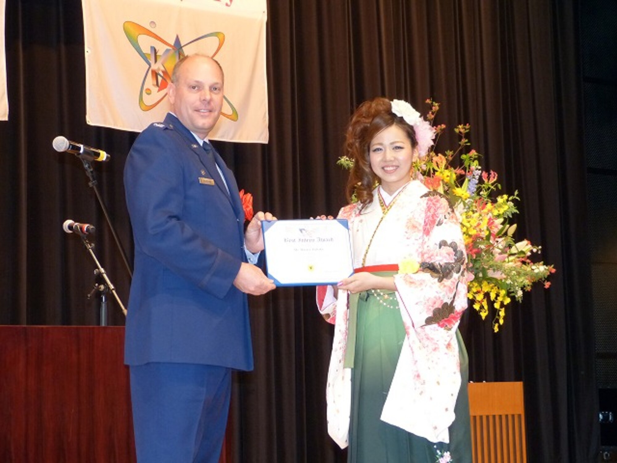 Minayo Tsuhako, a Kadena Language Institute student, is awarded the 18th Wing Best Intern Award by Col. Jeffrey Ullmann, 18th Mission Support Group commander, during the KLI graduation ceremony in Kadena Town, Okinawa, Japan, March 7, 2013. Tsuhako and eight second-year students interned at various locations around Kadena Air Base in 2012 to improve their English conversation skills. KLI is a two-year vocational school where students ages 19-24 learn many different languages including English, and study Okinawan culture. (Photo courtesy of KLI)