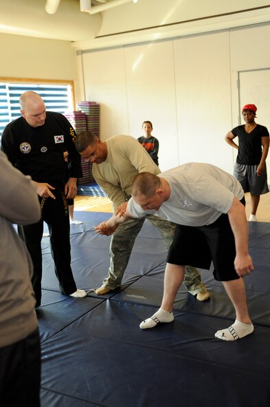 Chief Master Sgt. Philliip Robinson, middle, 8th Fighter Wing command chief, practices an arm-bar takedown technique on Staff Sgt. Jonathan Mollison, 8th Comptroller Squadron, at Kunsan Air Base, Republic of Korea, March 6, 2013.  Taekwondo instructors from Osan Air Base, Republic of Korea, also taught Wolf Pack members how to thwart wrist grabs, neck chokes, bear hugs and other self-defense techniques. (U.S. Air Force photo by Senior Airman Marcus Morris/Released)
