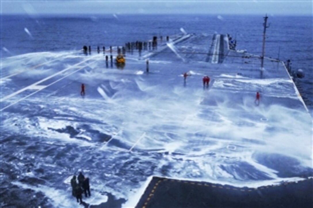 U.S. sailors wash down the flight deck after performing an aqueous film forming foam system test aboard the aircraft carrier USS Ronald Reagan in the Pacific Ocean, March 10, 2013. The Reagan is under way conducting sea trials.