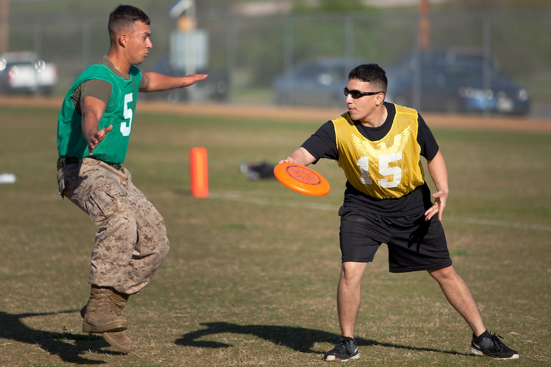 Staff Sgt. Ricardo R. Paez, right, a helicopter mechanic with Wounded Warrior Battalion West, makes a pass to a teammate during an ultimate Frisbee tournament at the Camp Horno Football Field here March 13.