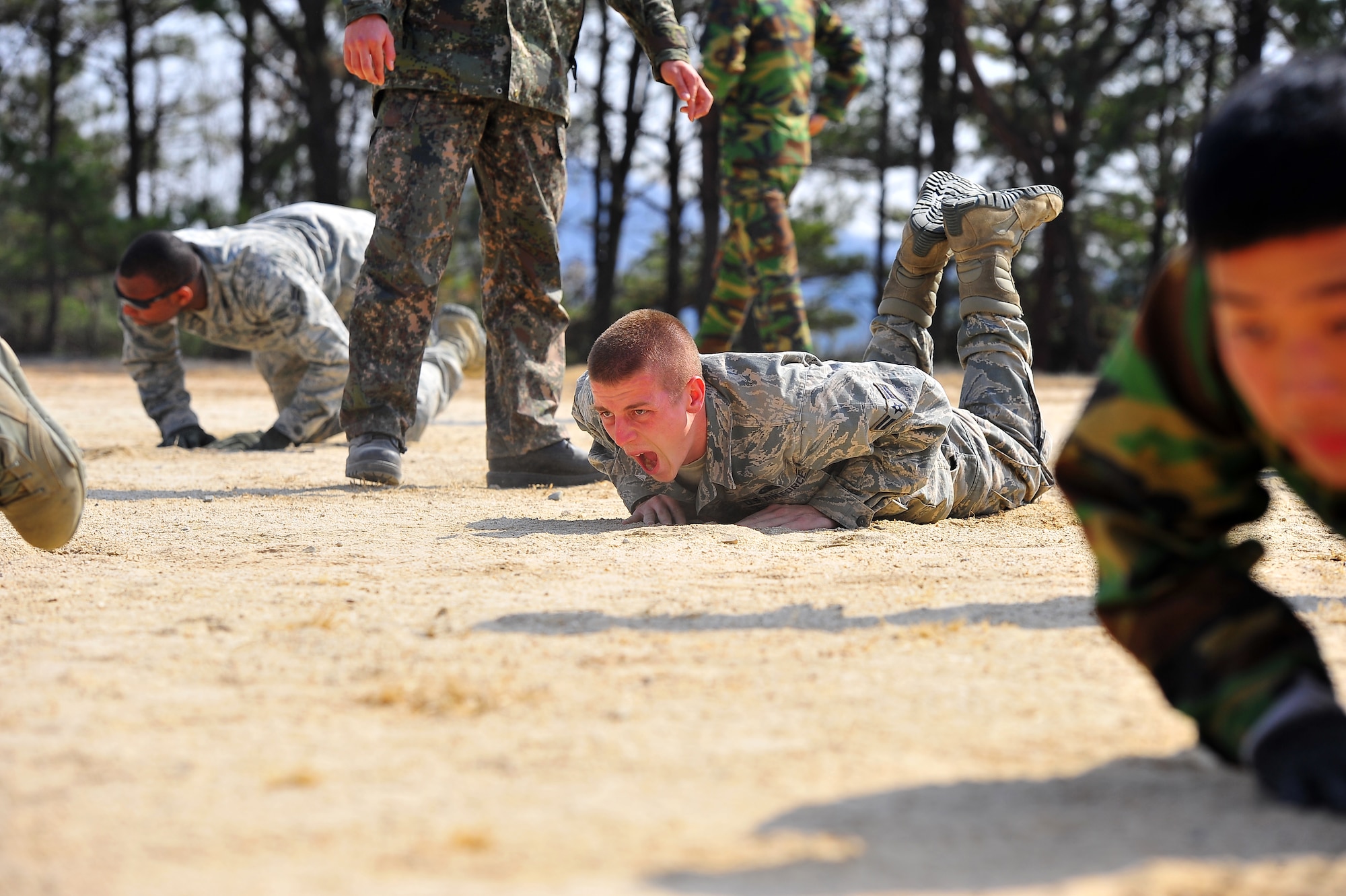 Airman 1st Class Charles Manarino, 51st Security Forces Squadron member, works through a physical training session as an instructor stands over him at the Jinjui Air Force Education and Training Command Republic of Korea, March 6, 2013.  The SFS Airmen learn different styles and techniques for PT training with ROKAF air police. (U.S. Air Force photo/Staff Sgt. Emerson Nuñez)