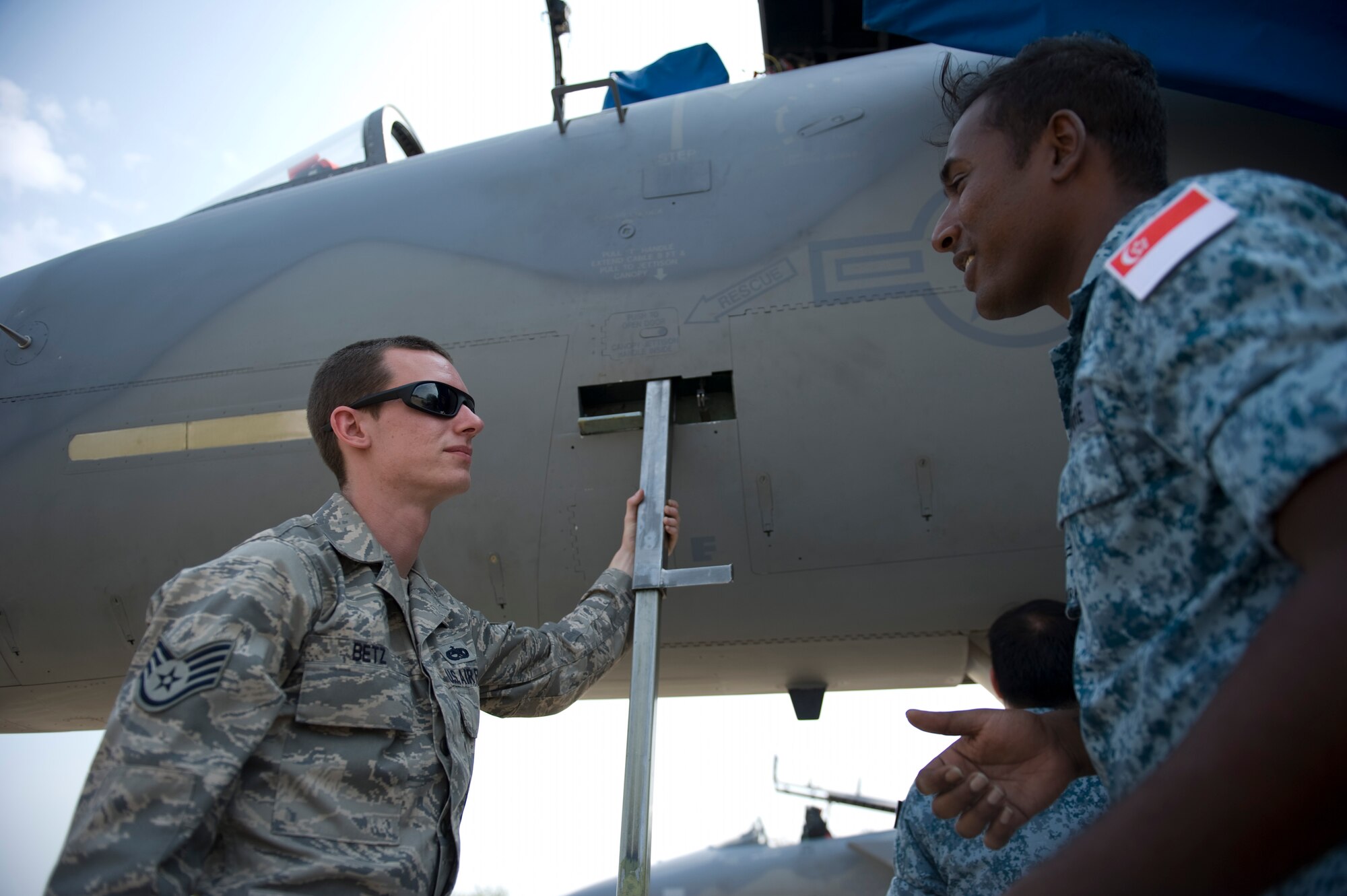 Staff Sgt. Curtis Betz, an F-15C Eagle crew chief, talks with a Republic of SIngapore Airman during an F-15 aircraft maintenance exchange between U.S. and Republic of Singapore Airmen during Cope Tiger 13 at Korat Royal Thai Air Force Base, Thailand, March 12, 2013.  Betz is assigned to the 18th Aircraft Maintenance Squadron at Kadena Air Base, Japan. Cope Tiger is an annual multilateral exercise designed to improve readiness and cooperation between U.S., Thai and Singaporean forces. (U.S. Air Force photo/2nd Lt. Jake Bailey)