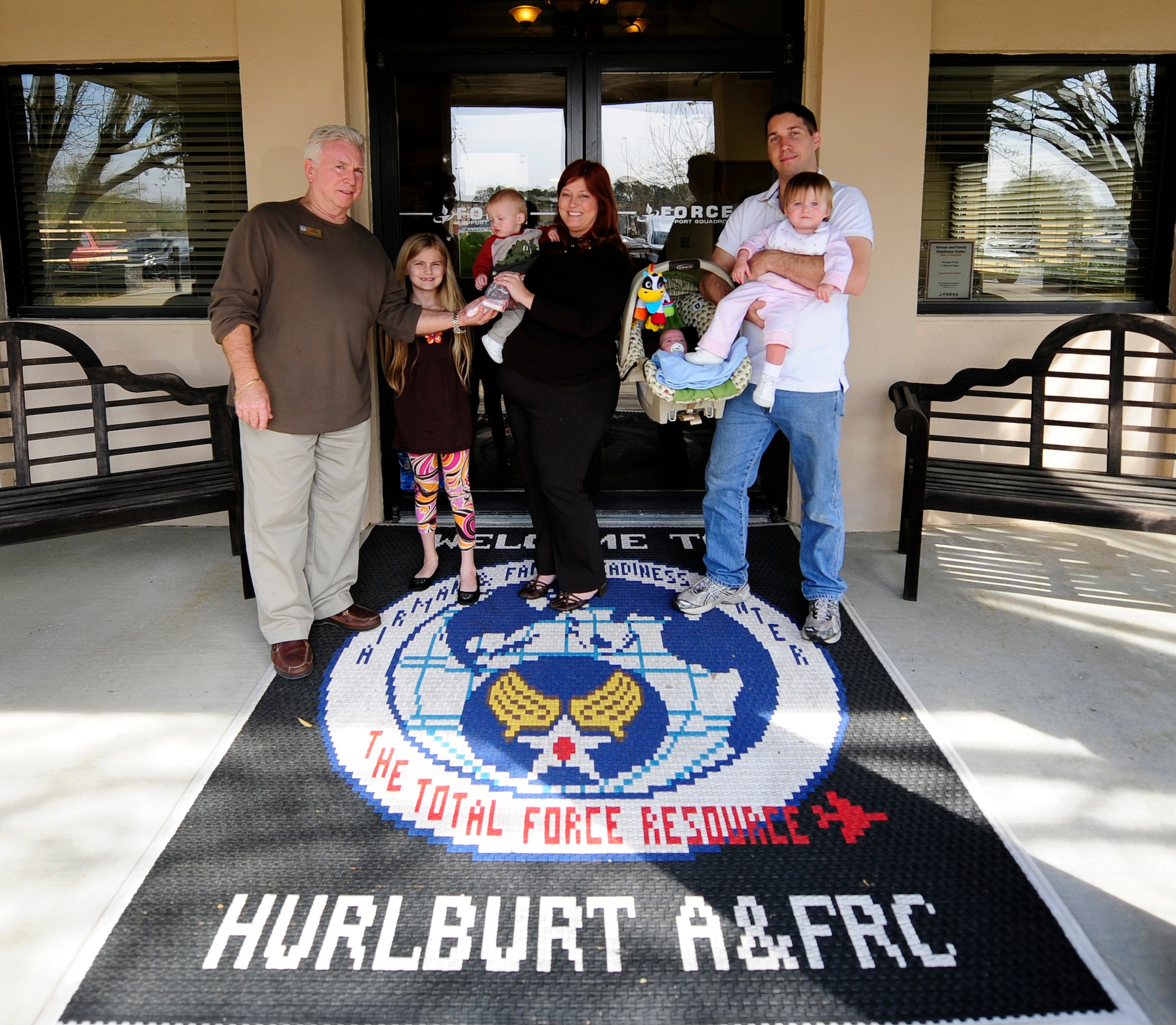 U.S. Air Force Staff Sgt. Benjamin Bagley, a crew chief from the 801st Special Operations Aircraft Maintenance Squadron, (right) and his family received five rolls of quarters totaling $50 from Tom Snyder (left), a community readiness consultant for 1st Special Operation Force Support Squadron, for winning the 'Change to Save' contest on  Hurlburt Field, Fla., March. 7, 2013. The family located more than $100 dollars worth of loose change, winning the contest. (U.S. Air Force Photo by Senior Airman Kentavist P. Brackin)
