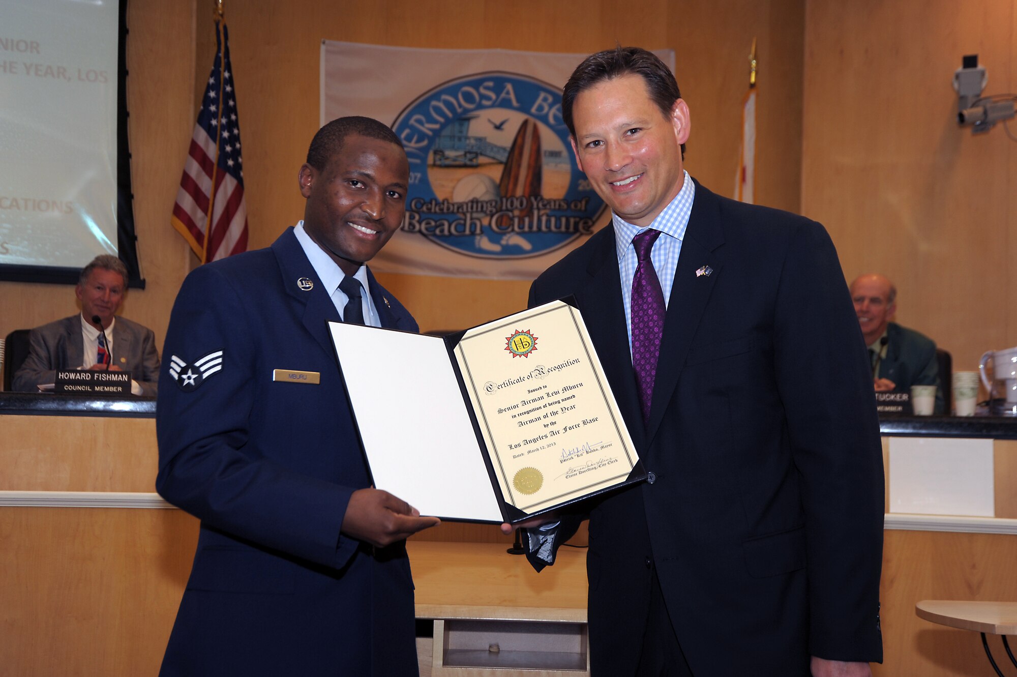 Senior Airman Levi Mburu (left) receives a certificate of recognition from Hermosa Beach Mayor, Patrick Bobko, during a council meeting Mar 12, 2013. SrA Mburu was selected as the Airman of the Year for Los Angeles Air Force Base, home of the Space and Missile Systems Center in El Segundo, Calif.