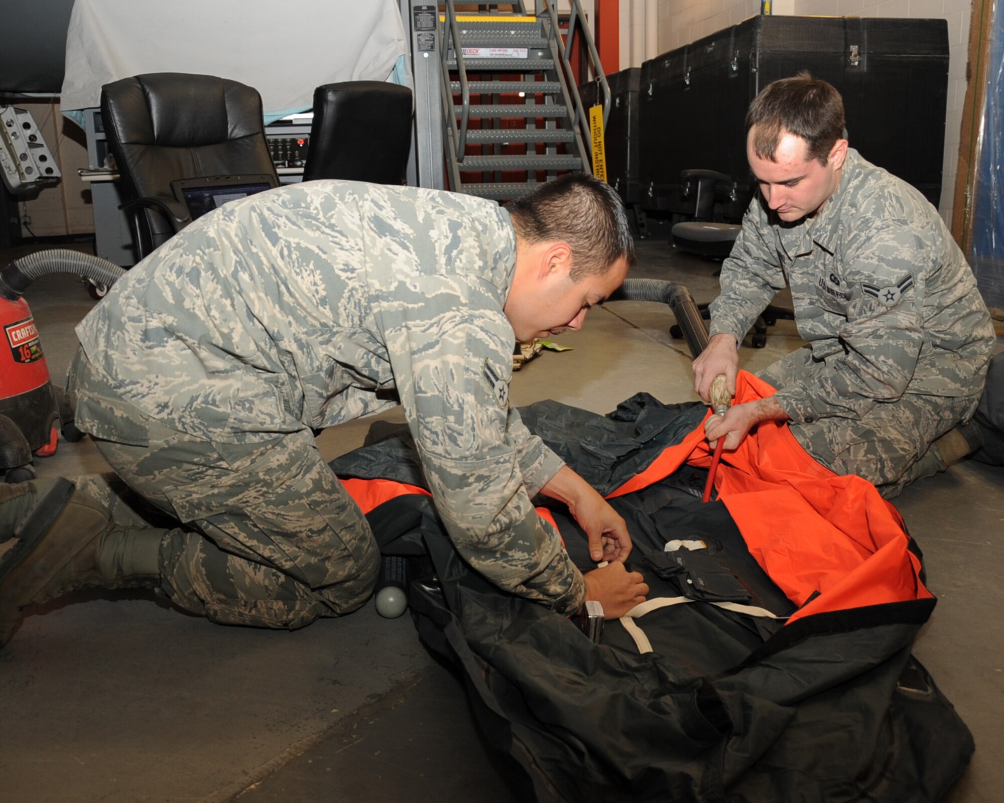Airmen 1st Class Todd Billow and Patrick Russell, 2nd Operation Support Squadron Aircrew Flight Equipment, pack a one-man life raft on Barksdale Air Force Base, La., March 13. The AFE flight line section is in charge of installing and inspecting all survival kits on the B-52H Stratofortress.  (U.S. Air Force photo/Senior Airman Sean Martin)