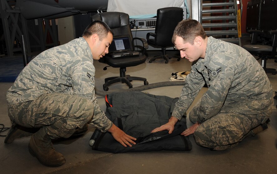 Airmen 1st Class Todd Billow and Patrick Russell, 2nd Operation Support Squadron Aircrew Flight Equipment, pack a one-man life raft on Barksdale Air Force Base, La., March 13. The AFE flight line section is in charge of installing and inspecting all survival kits on the B-52H Stratofortress.  (U.S. Air Force photo/Senior Airman Sean Martin)