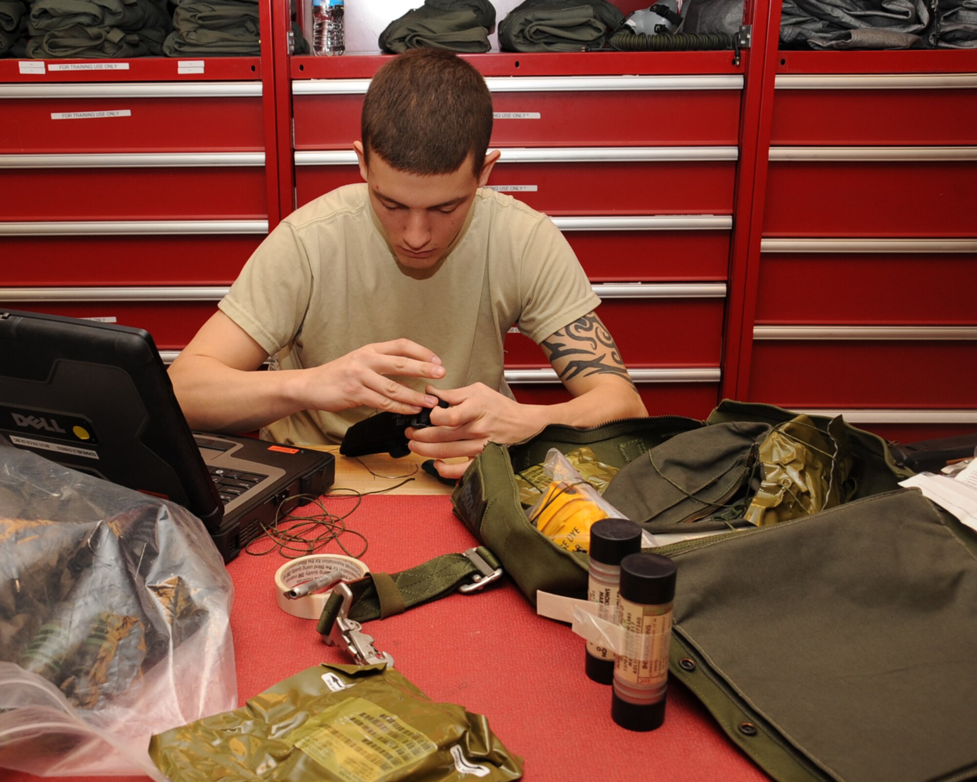 Airman 1st Class Michael Fields, 2nd Operation Support Squadron Aircrew Flight Equipment, works on a soft survival kit on Barksdale Air Force Base, La., March 13. The soft kit includes life-saving equipment in the event of an egress to include flares, sea dye, a strobe light, tourniquet, knife and candle. (U.S. Air Force photo/Senior Airman Sean Martin)