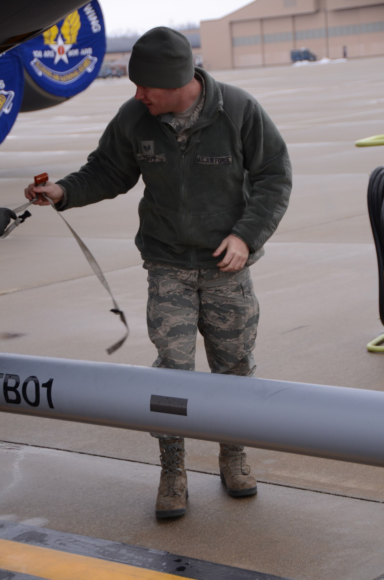 After positioning a KC-135R Stratotanker aircraft on the flightline at Scott Air Force Base, Ill. in preparation for a scheduled flight, Staff Sgt. Mark Trapp, a crew chief for the 906th Air Refueling Squadron, removes a strap that helped secure the aircraft's bottom hatches during movement prior to flight.  The aircraft, assigned to the 126th Air Refueling Wing, Illinois Air National Guard, was moved back to the flightline after a brief snowstorm passed through the area on March 5, 2013.  The 906 ARS is an Active Associate squadron of the 126th Air Refueling Wing, Illinois Air National Guard, and is comprised of Active Duty Air Force members. (National Guard photo by Airman 1st Class Elise Stout)