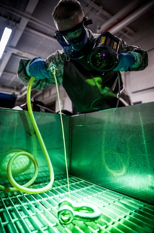 Staff Sgt. John Price, 437th Maintenance Squadron non-destructive inspector, sprays dye on a horseshoe shaped collar March 8, 2013, at Joint Base Charleston – Air Base, S.C. After the dye dries, the part is placed under black lights to reveal cracks or flaws in the metal. The inspection process can take up to an hour for each part, and also includes three separate chemical baths and a drying machine. (U.S. Air Force photo/Senior Airman Dennis Sloan)