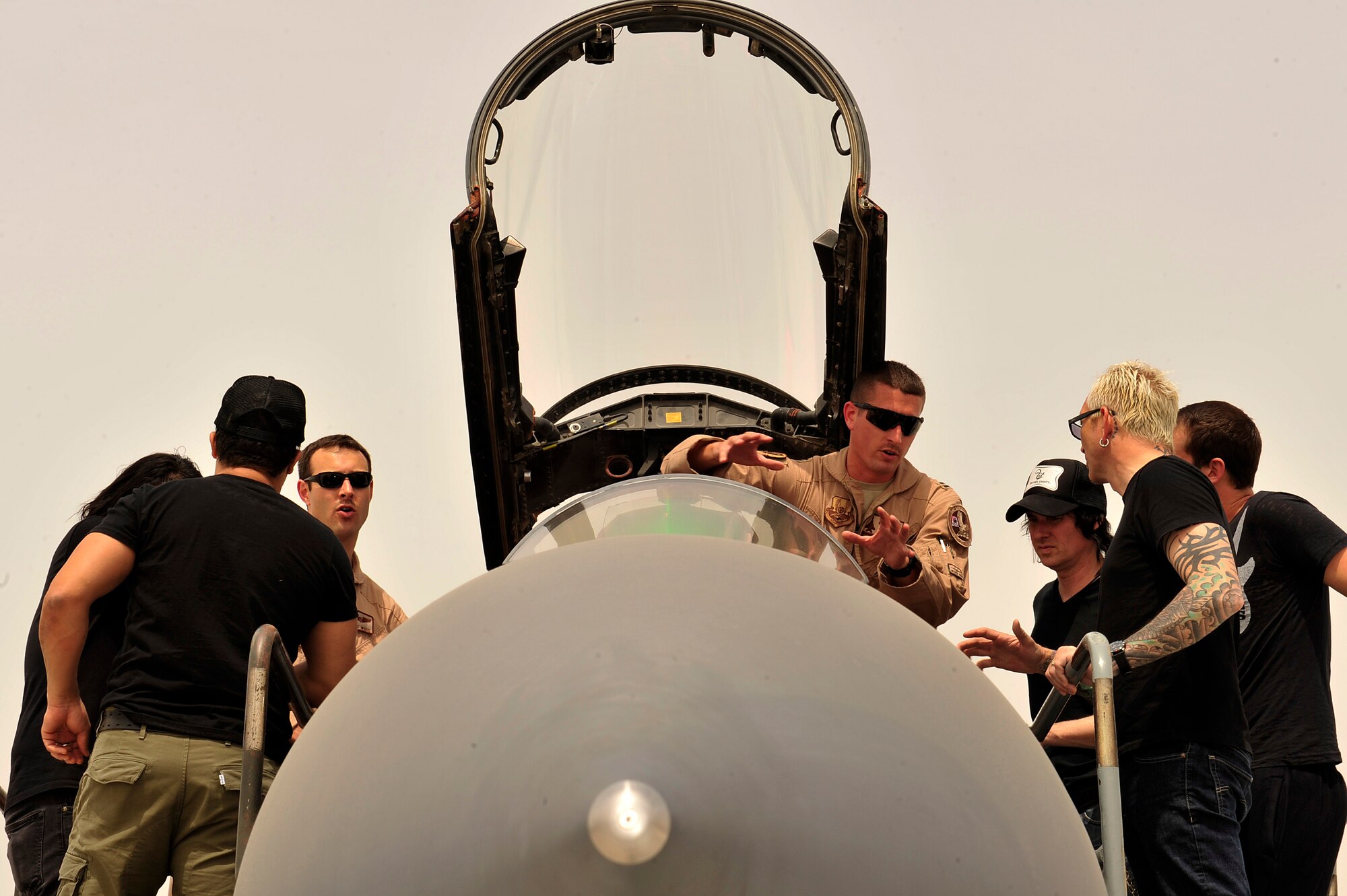 U.S. Air Force Capts. Dale Wood, 494th Expeditionary Fighter Squadron weapons system officer, and Rory Klepper, pilot, give a tour of an aircraft to members of Everclear at an undisclosed location in Southwest Asia Mar. 10, 2013. The American rock band visited Airmen and Soldiers and performed a concert of their greatest hits for the 380th Air Expeditionary Wing. (U.S. Air Force photo by Tech. Sgt. Christina M. Styer/Released)