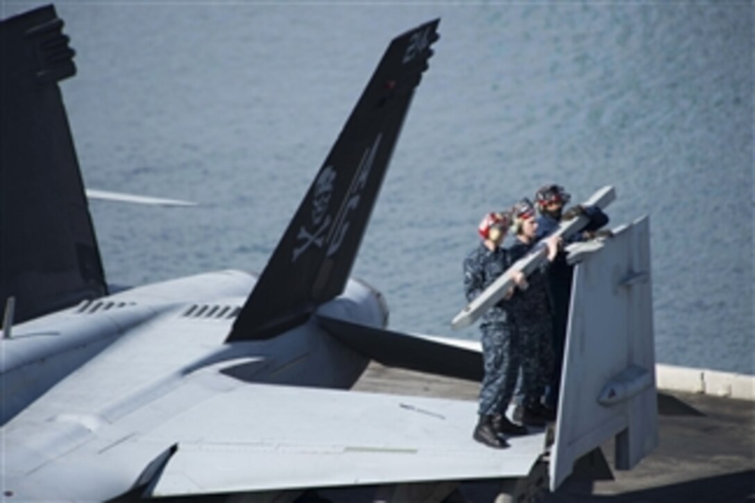 Sailors remove a bomb rack unit from the wing tip of an F/A-18F Super Hornet parked on the flight deck of the aircraft carrier USS Dwight D. Eisenhower (CVN 69) in Marseille, France, on March 10, 2013. Eisenhower is deployed to the 5th & 6th Fleet areas of responsibility to conduct maritime security operations and theater security cooperation efforts.  