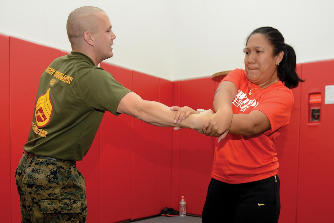 Staff Sgt. Ryan J. Ward, and Rowena Untalasco practice techniques during a self-defense course March 6 at the Ironworks Gym at Camp Courtney. The course focused on teaching basic defense techniques for use against larger or stronger attackers and was held in response to feedback from Marine spouses who attended 9th Engineer Support Battalion’s recent Jane Wayne Day. The Marine Corps martial arts program training piqued the interest of the spouses. Ward is a career planner with 9th ESB, 3rd Marine Logistics Group, III Marine Expeditionary Force. Untalasco is a Marine spouse. 