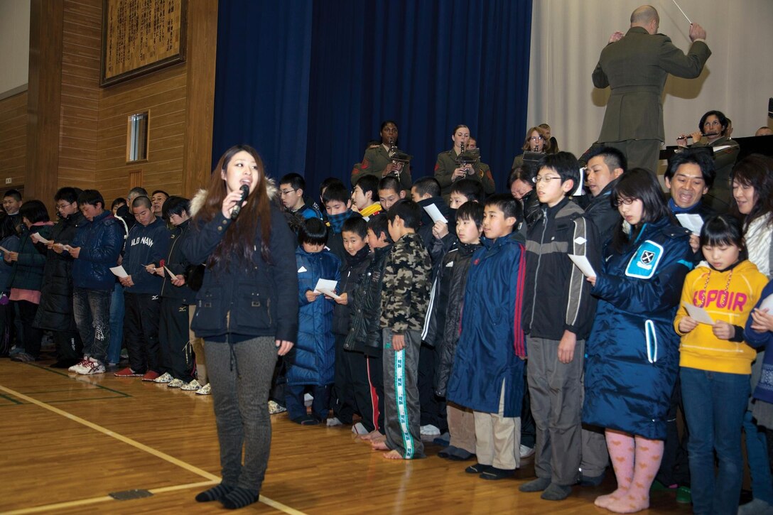 Haruna Kinoshita, children and families from Oshima Island and the III Marine Expeditionary Force Band perform a song at the close of a memorial ceremony March 11 at Oshima Elementary School. The ceremony honored the lives lost during the Great East Japan Earthquake and subsequent tsunami of March 11, 2011. Kinoshita is a volunteer performer. 