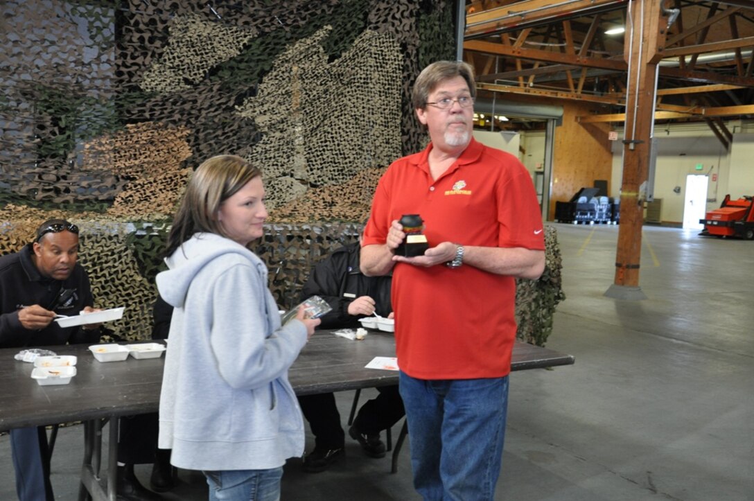 Stacey Decker, a supply technician with Fleet Support Division on Marine Corps Logistics Base Barstow, Yermo Annex, receives a trophy from Gregory Johnson, FSD’s chili cook-off committee chairman, for winning the 2nd annual chili cook-off challenge, March 6. The friendly competition raises money for FSD’s employee appreciation day.
