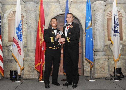 Coast Guard Cmdr. Eugenio Anzano, U.S. Coast Guard Cryptologic Unit senior commanding officer, presents Lt. Lance Leone, Coast Guard Medical Liaison officer, with the Coast Guard company grade officer of the year award.