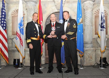 Rear Adm. William Roberts, Medical Education and Training Campus commandant, and Master Chief Petty Officer Rusty Perry, Navy Medicine Education and Training Command command master chief, present Anthony Ortiz, Navy Technical Training Center, with the Navy civilian supervisory category I of the year award.