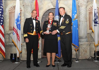 Rear Adm. William Roberts, Medical Education and Training Campus commandant, and Master Chief Petty Officer Rusty Perry, Navy Medicine Education and Training Command command master chief, present Petty Officer 1st Class Tanya Austin, Navy Operational Support Center, with the Navy NCO of the year award.