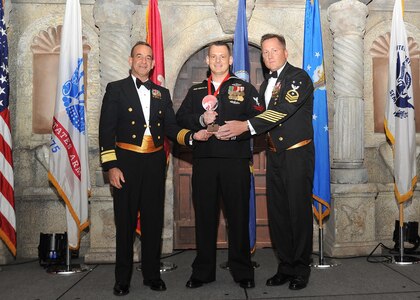 Rear Adm. William Roberts, Medical Education and Training Campus commandant, and Master Chief Petty Officer Rusty Perry, Navy Medicine Education and Training Command command master chief, present Petty Officer 2nd Class Jacob Miller, Navy Medicine Training Support Center, with the Navy junior enlisted member of the year award.