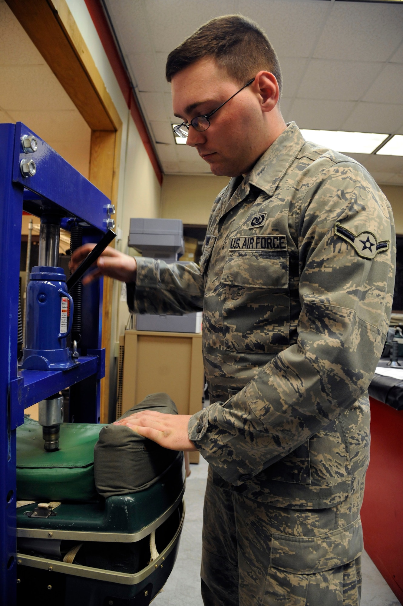 Airman Steven Snyder, 2nd Operations Support Squadron Aircrew Flight Equipment, uses a hydraulic jack to seal an aircrew survival kit on Barksdale Air Force Base, La., March 14. AFE Airmen must maintain and install survival kits aircrew will need if they eject over hostile territory. (U.S. Air Force photo/Airman 1st Class Andrew Moua)