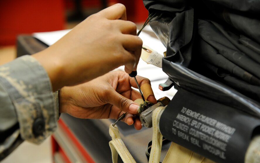 Airman 1st Class Karin Puckett, 2nd Operations Support Squadron Aircrew Flight Equipment, connects a life raft bottle to a life raft on Barksdale Air Force Base, La., March 14. The bottle inflates the raft which is included in a survival kit aircrew need to survive in the event they eject over hostile territory. (U.S. Air Force photo/Airman 1st Class Andrew Moua)