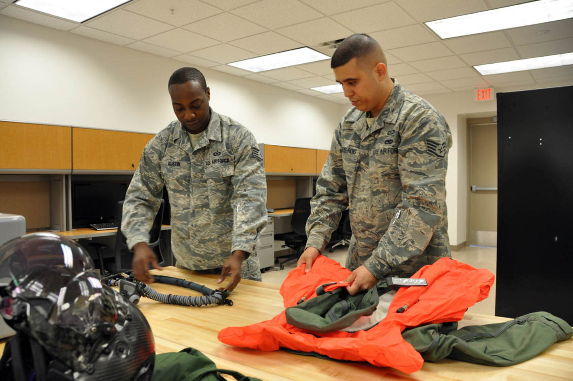 NELLIS AIR FORCE BASE, Nev. -- (Right to left) Staff Sgt. Enrique Dejesus-Roig, 706th Fighter Squadron, conducts a leakage test on a life preserver, while Staff Sgt. Willis Austin, 422nd Test and Evaluation Squadron, inpsects a pilot interface connector for holes and tears. Both Airmen are Aircrew Flight Equipment craftsmen assigned to the new F-35 Lightning II program here. (U.S. Air Force photo/Maj. Jessica Martin)